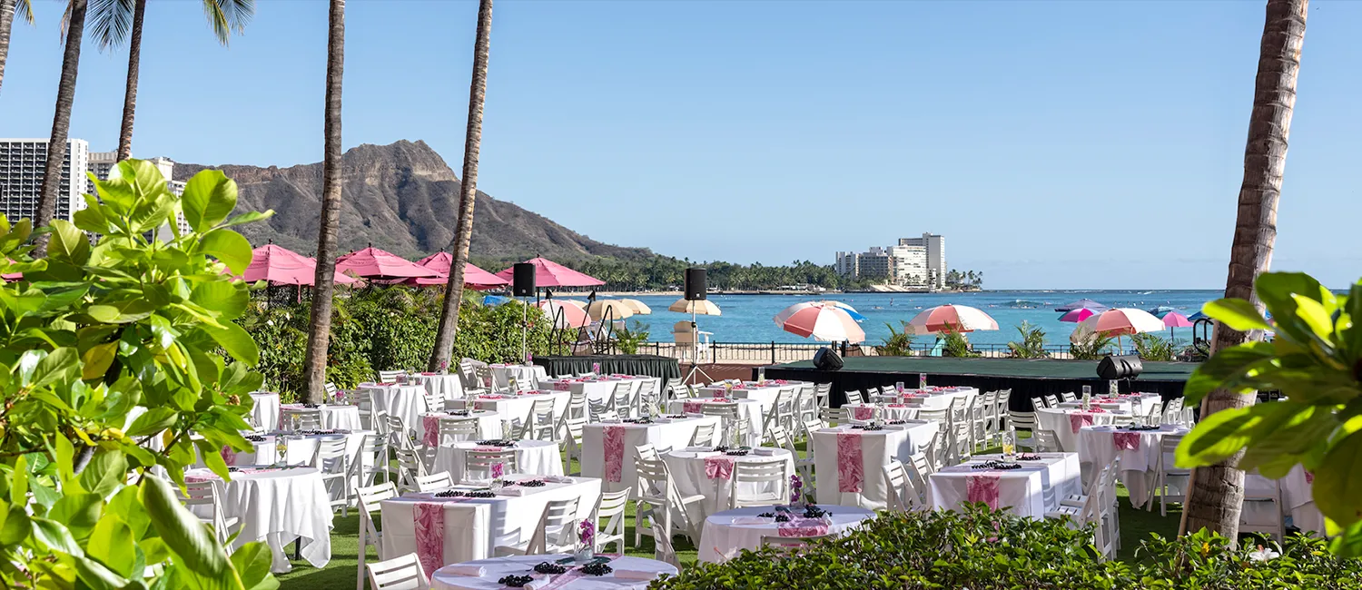 An elegant outdoor dinner setup for Ahaʻaina, A Royal Hawaiian Luau, overlooking Waikiki Beach and Diamond Head