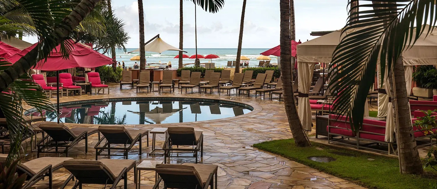 Pool area lined with chairs and umbrellas.