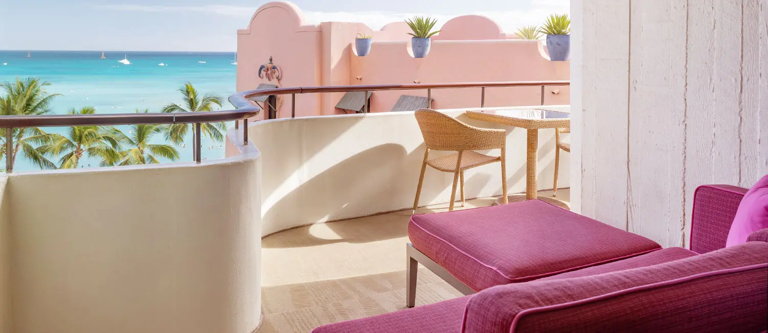 Beige balcony overlooking Waikiki Beach with a pink daybed accent.