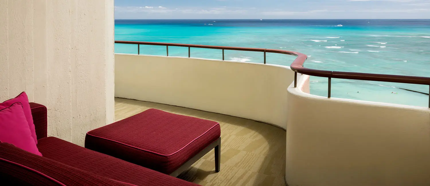 Corner balcony with pink daybed overlooking Waikiki Beach.