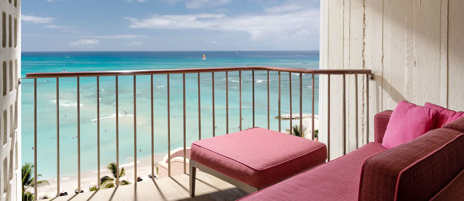Balcony with pink daybed offering a view of Waikiki Beach.