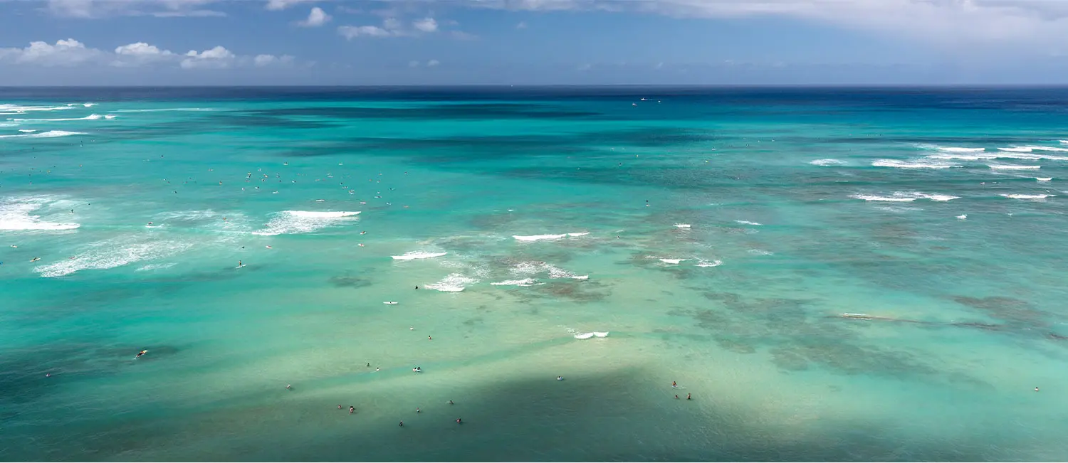 Panoramic view of Waikiki Beach from upper floors with gentle waves below.