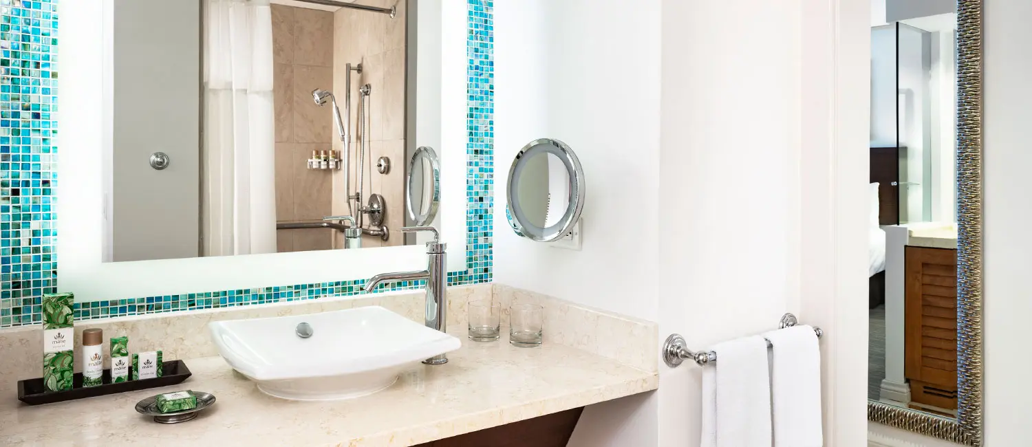 Bathroom with turquoise tiles featuring Malie Organics amenities.