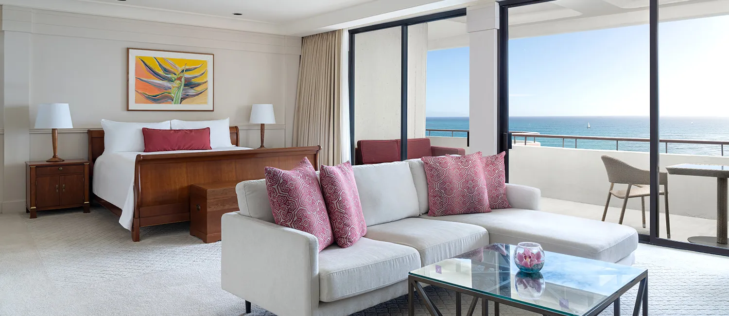 The Ali‘i Suite guest room combining a bedroom and living area with an ocean view.