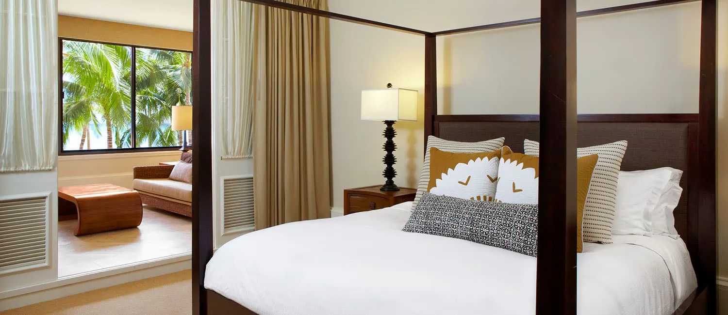 The bedroom of the Queen Ka‘ahumanu Suite featuring a four-poster bed and a sofa area.