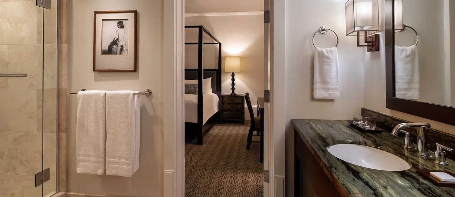The Queen Ka‘ahumanu Suite bathroom with a vanity and shower, showing the bedroom beyond.