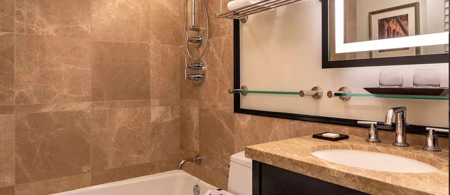 Bathroom featuring marble-style walls and a bathtub.