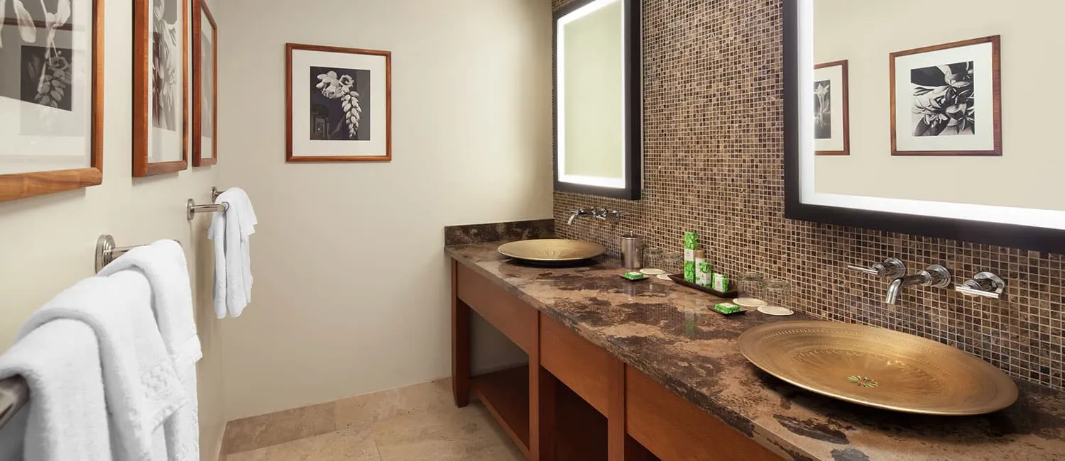 Bathroom featuring mosaic tile walls and gold vessel sinks.